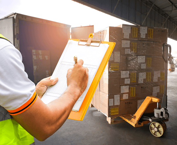 Person checking documents next to stacked boxes